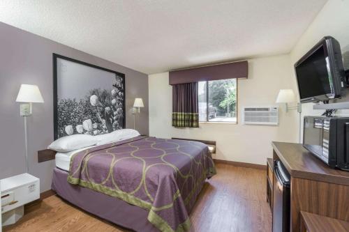 a hotel room with a bed and a flat screen tv at Super 8 by Wyndham Zanesville in Zanesville