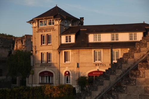 un grande edificio in mattoni con torre dell'orologio di LOGIS HOTEL BELLEVUE RESTAURANT LA POMME d'OR a Coucy-le-Château-Auffrique