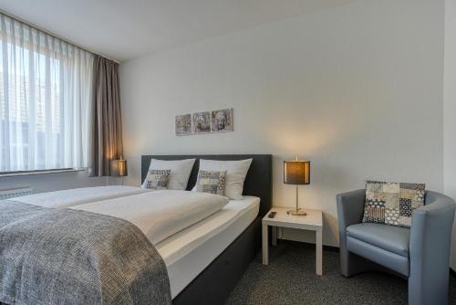 een slaapkamer met een groot bed en een blauwe stoel bij Hotel Carlton in Dortmund