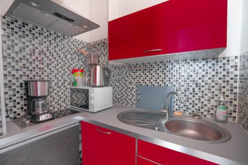 La cuisine est équipée d'un évier et d'une armoire rouge. dans l'établissement Studio Centre belle vue mer, à Dinard