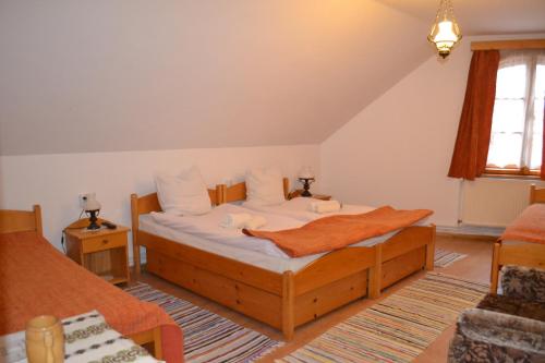 a bedroom with a bed with white sheets and an orange blanket at Enikő Vendégház in Cernatu de Sus