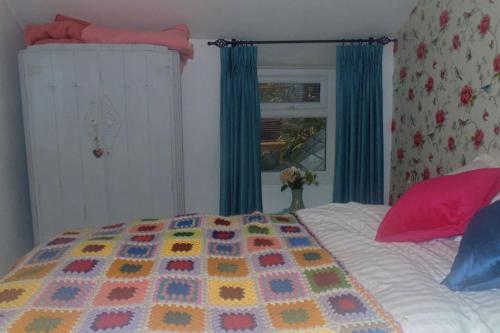 a bed with a colorful quilt on top of it at Cosy cottage with mountain views in Blaenau-Ffestiniog