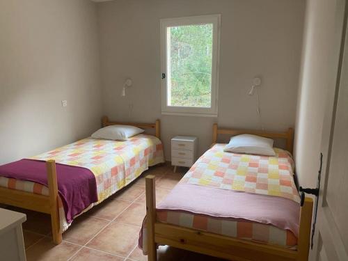 deux lits dans une chambre avec une fenêtre dans l'établissement Chez Laura près du Pont d'Arc, à Salavas