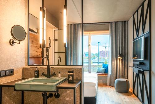 a bathroom with a sink and a living room at Me and All Hotel Kiel, by Hyatt in Kiel