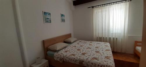 a small bedroom with a bed and a window at Apartments Dida moj in Šmrika
