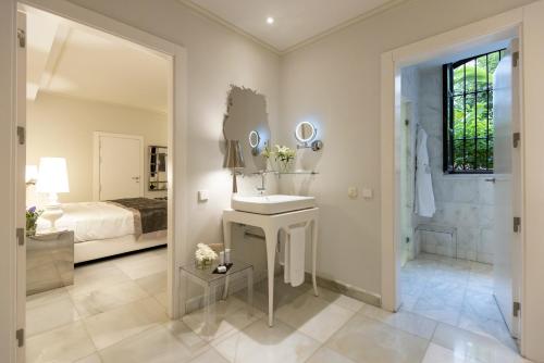 a bathroom with a sink and a bed and a mirror at Hospes Palacio de los Patos, a Member of Design Hotels in Granada