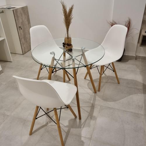 a glass table and four white chairs in a room at AZ Suites Resistencia in Resistencia