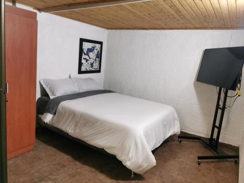 a bedroom with a bed and a flat screen tv at Portal Norte 170 ACOGEDORAS HABITACIONES CON TODOS LOS SERVICIOS in Bogotá