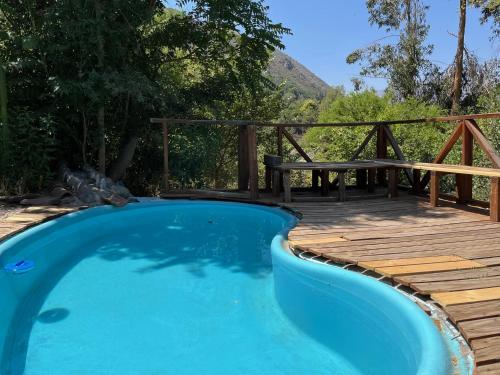 a swimming pool next to a wooden deck with a picnic table at Alojamiento Nido de Almas en Cajón del Maipo in Santiago