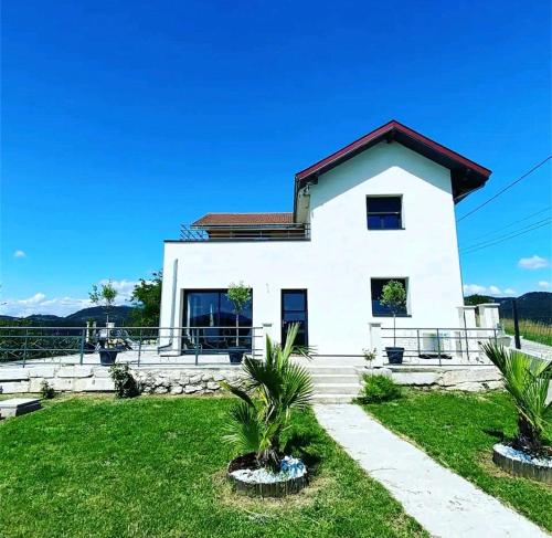 une maison blanche avec des palmiers devant elle dans l'établissement Villa Bellevue "Rez-de-chaussée", à Belley