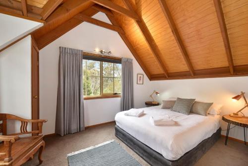 a bedroom with a large bed and a wooden ceiling at The Lodge Blackheath in Blackheath