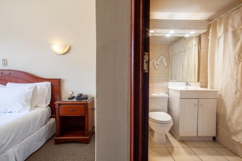 a bathroom with a bed and a toilet and a sink at HOTEL EL DORADO in Concepción