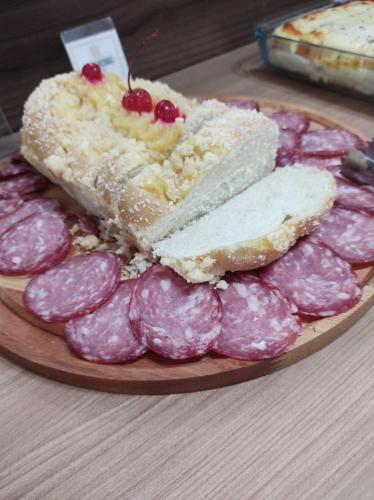 a plate of food with a piece of cake and a pile of pink meat at Nova Vicenza Hotel in Farroupilha