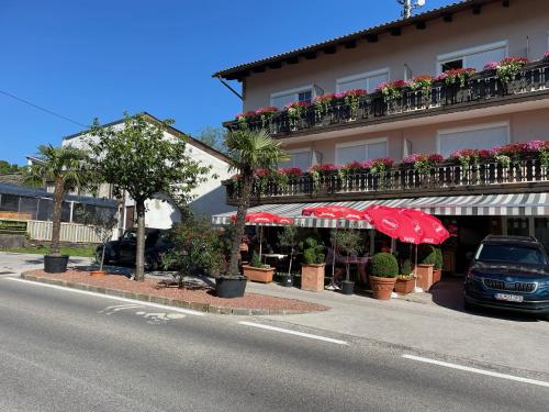 a building with flowers and umbrellas on the side of a street at Gästehaus Trink B&B in Drobollach am Faakersee