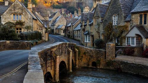 an old stone bridge over a street in a village at Luxury Cotswolds Cottage optional Hot Tub, Castle Combe in Castle Combe