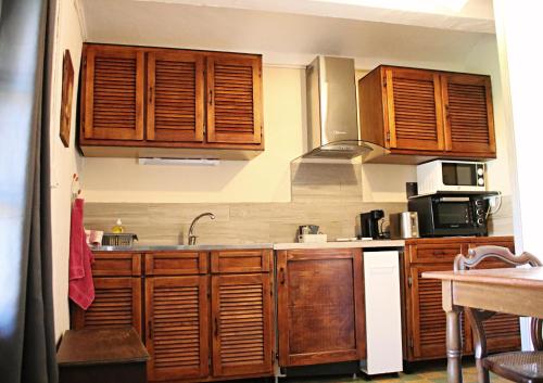 une cuisine avec des armoires en bois et un évier dans l'établissement La ferme Ranc - gite le cosy, à Gagnières