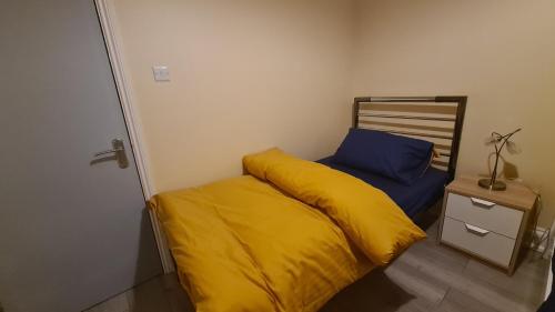 a small bedroom with a yellow bed and a night stand at Entire 2 Bedroom Home/Flat In London, Central Line in London