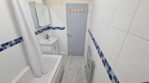 a white bathroom with a sink and a tub and a toilet at Entire 2 Bedroom Home/Flat In London, Central Line in London