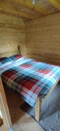 een bed in een houten kamer in een hut bij The Willow Cabin - Wild Escapes Wrenbury off grid glamping - ages 12 and over in Wrenbury