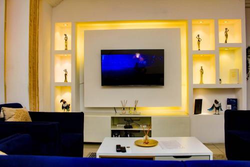a living room with a tv on a wall at Appartement cosy blue bonapriso in Douala