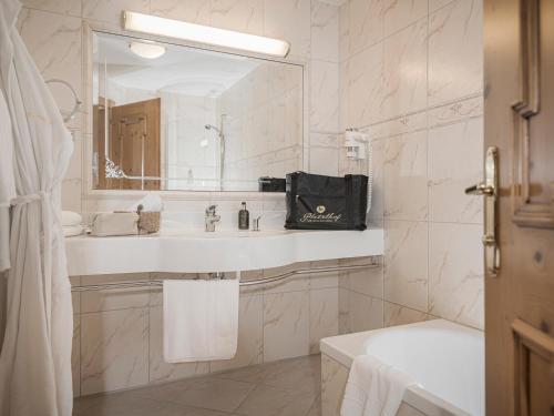 a white bathroom with a sink and a mirror at Platzlhof - Mein Hotel im Zillertal in Ried im Zillertal