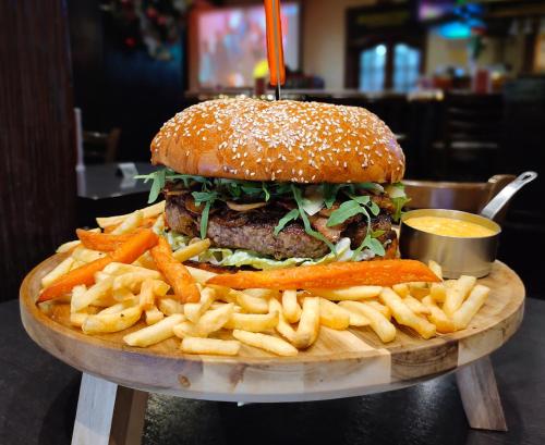 a hamburger and french fries on a wooden plate at Millennium Plaza Downtown Suites in Dubai