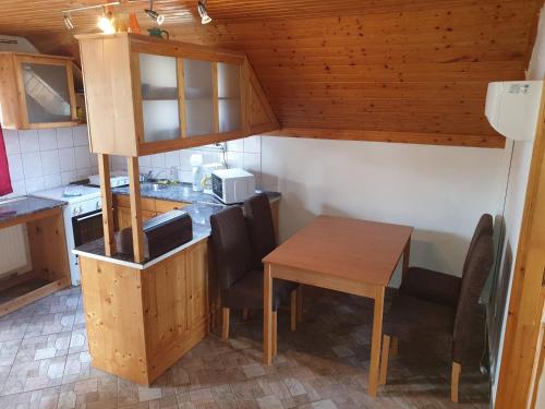una pequeña cocina con mesa de madera y sillas en Vilmos Pince Fogadó en Hévíz