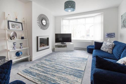 a living room with a blue couch and a tv at The Tardis 5 bedroom, 3 bathroom Oxford City Oasis with Free Parking in Oxford