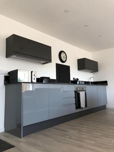 a kitchen with a counter with a clock on the wall at Meadow Cottage. Pretty modern cottage close to Woolacombe and Lee in Ilfracombe