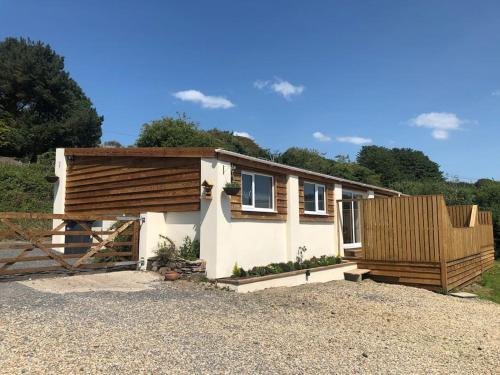 ein kleines Haus mit einem Holzzaun davor in der Unterkunft Meadow Cottage. Pretty modern cottage close to Woolacombe and Lee in Ilfracombe