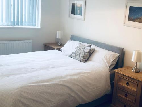 ein Schlafzimmer mit einem großen weißen Bett mit zwei Nachttischen in der Unterkunft Meadow Cottage. Pretty modern cottage close to Woolacombe and Lee in Ilfracombe