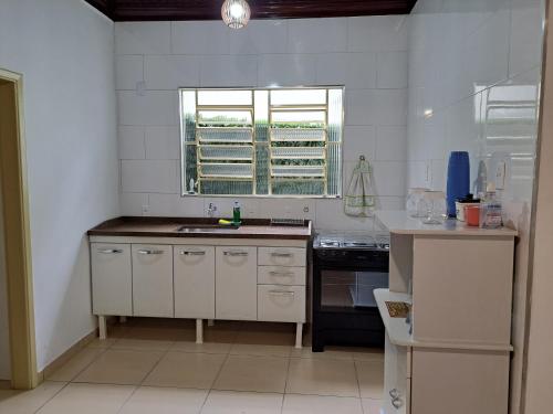 a white kitchen with a sink and a window at CASA LUGAR TOP - prefeitura, UNITAU, hospital e Av do Povo in Taubaté