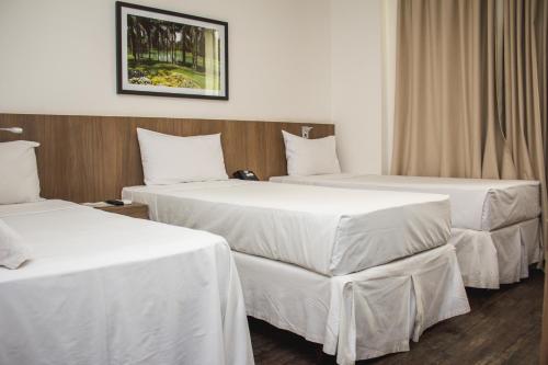 2 camas en una habitación de hotel con sábanas blancas en Nobile Hotel Belo Horizonte, en Belo Horizonte