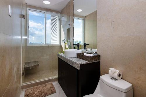 a bathroom with a toilet and a sink and a window at Amara, depa con vista al mar in Cancún