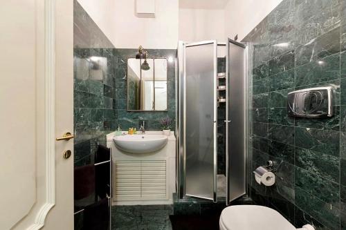 La salle de bains est pourvue de carrelage vert, d'un lavabo et d'une douche. dans l'établissement Sweethome Crispi, à Rome