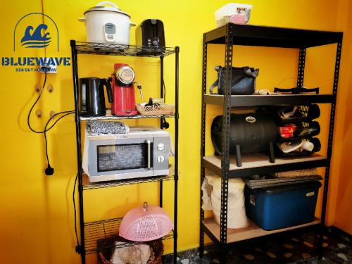 a kitchen with a microwave and a shelf with food at Bluewave Sea Out Seaview Homestay in Kuah