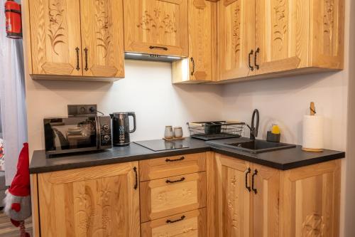 a kitchen with wooden cabinets and a microwave at Modrzewiowa Ostoja II in Kluszkowce