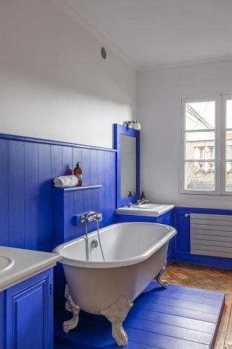 La salle de bains bleue est pourvue d'une baignoire blanche et d'un lavabo. dans l'établissement Le Cambronne - en Bail Mobilité, à Nantes