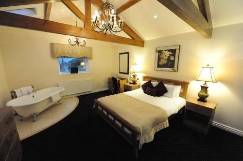 a bedroom with a bed and a tub and a sink at Kings Croft Hotel in Pontefract