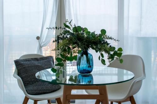 a blue vase on a glass table with two chairs at SUNNY SIDE I Turin Suite in Turin