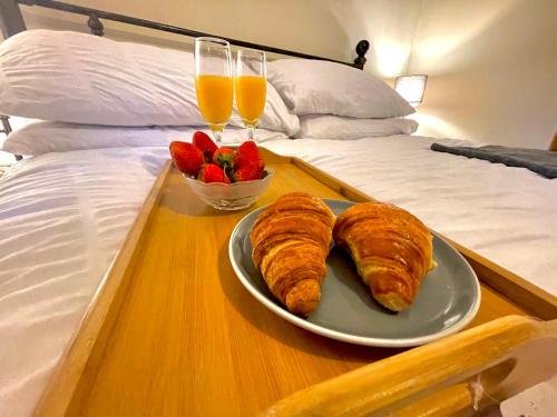 a tray with croissants and a bowl of fruit on a bed at Remarkable 1-Bed House NearZip World Snowdonia in Tanygrisiau