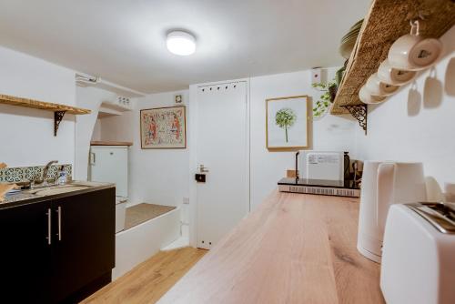 a kitchen with white walls and a wooden floor at The Summertown STUDIO 1BR & kitchenette in Oxford