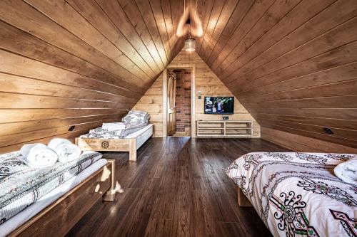 Dormitorio en cabaña de madera con 2 camas y TV en TATRAHOLIDAY- Domek Zbójnicki, en Bańska Wyżna
