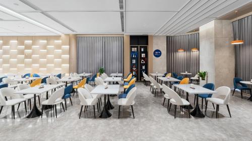 a dining room with white tables and chairs at Holiday Inn Express Qingdao Northern West Coast by IHG in Qingdao