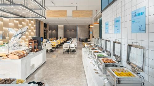 a restaurant with a buffet line with tables and chairs at Holiday Inn Express Qingdao Northern West Coast by IHG in Qingdao