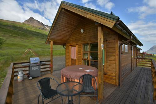 a cabin with a table and chairs on a deck at Sólbrekka Holiday Homes in Mjóifjörður