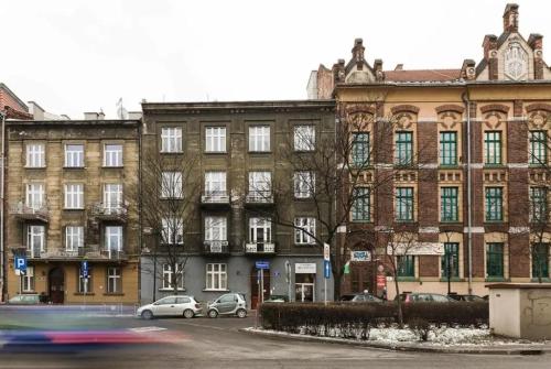 duży ceglany budynek z samochodami zaparkowanymi przed nim w obiekcie Room Tour Lubomirskiego 23 w Krakowie