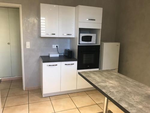 La cuisine est équipée de placards blancs, d'un réfrigérateur et d'un four micro-ondes. dans l'établissement Résidence privée calme 15 min à pied du centre parking gratuit, à Arles