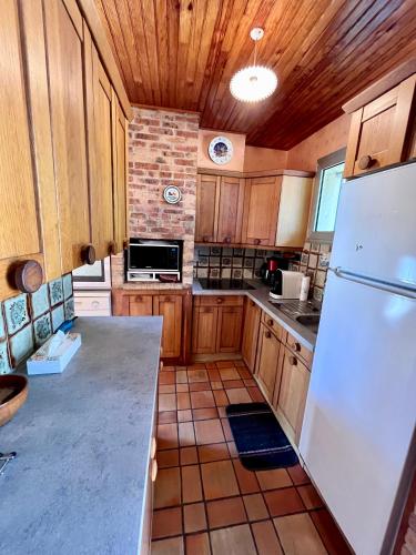 une cuisine avec des armoires en bois et un réfrigérateur blanc dans l'établissement Le Bonheur en Vacances ! :), à Lacanau