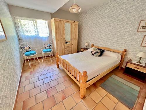 - une chambre avec un lit en bois et deux chaises dans l'établissement Le Bonheur en Vacances ! :), à Lacanau